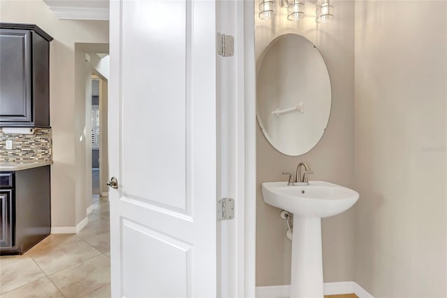 bathroom with tasteful backsplash, sink, and tile patterned flooring