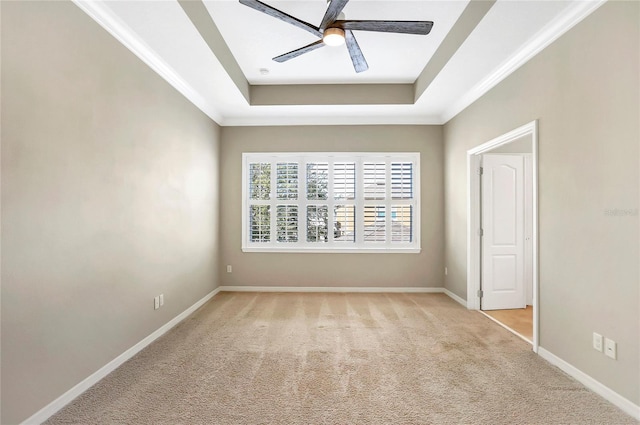 spare room with a raised ceiling, ornamental molding, light carpet, and ceiling fan