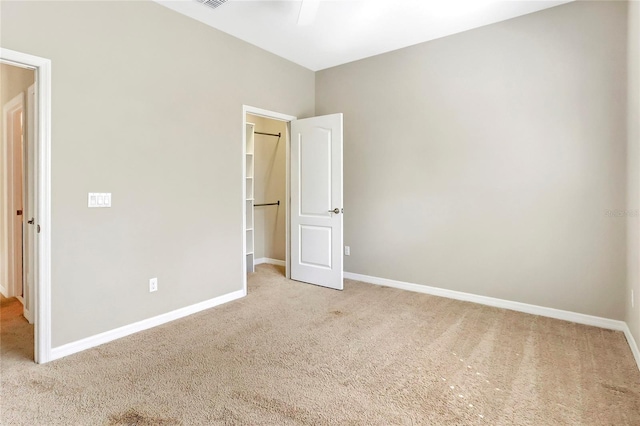 unfurnished bedroom featuring light carpet, a walk in closet, and a closet