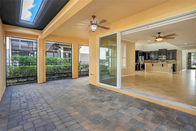 unfurnished sunroom with a skylight, a wealth of natural light, and ceiling fan