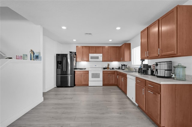 kitchen with white appliances, sink, and light hardwood / wood-style flooring