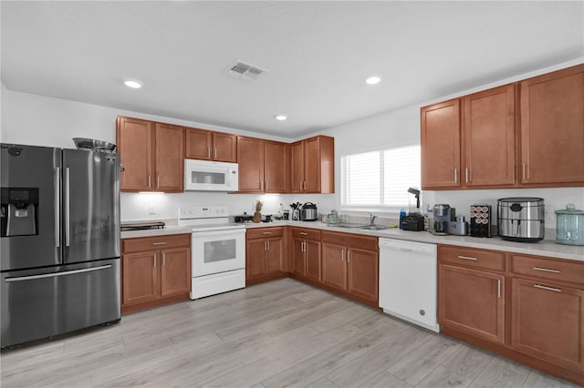 kitchen featuring sink, white appliances, and light wood-type flooring