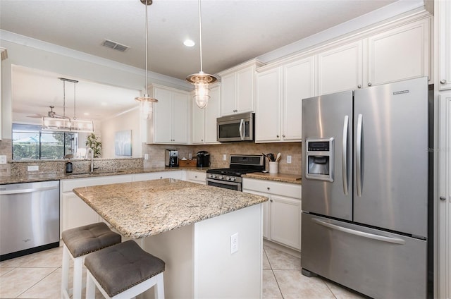 kitchen featuring light tile patterned floors, sink, appliances with stainless steel finishes, hanging light fixtures, and a kitchen island