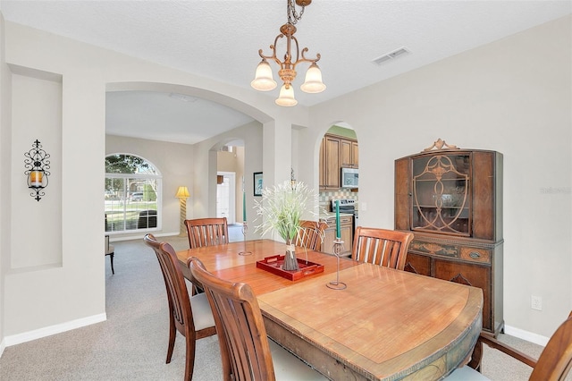 carpeted dining room featuring a chandelier and a textured ceiling