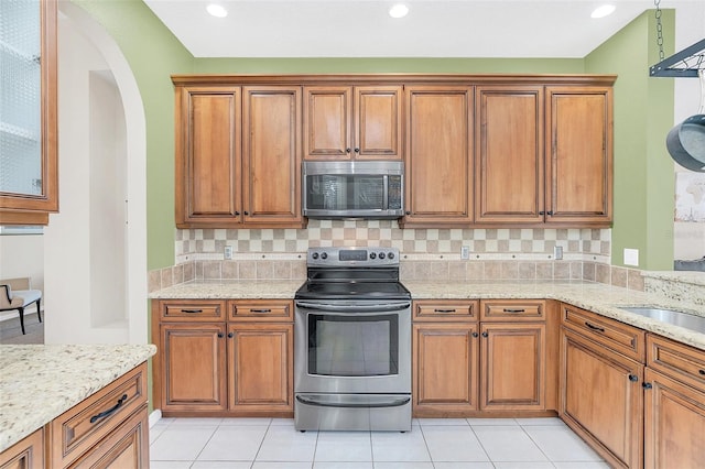 kitchen with light stone counters, light tile patterned floors, decorative backsplash, and appliances with stainless steel finishes