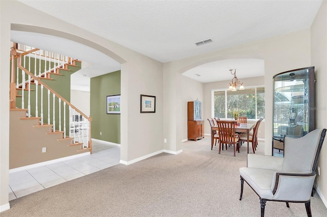 carpeted dining room with a textured ceiling and an inviting chandelier