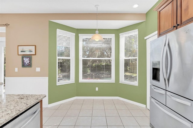 kitchen featuring hanging light fixtures, appliances with stainless steel finishes, light tile patterned floors, and light stone counters