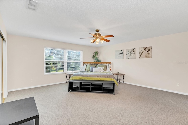 bedroom with ceiling fan, carpet, and a textured ceiling