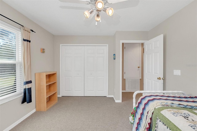 bedroom with light colored carpet, ceiling fan, and a closet