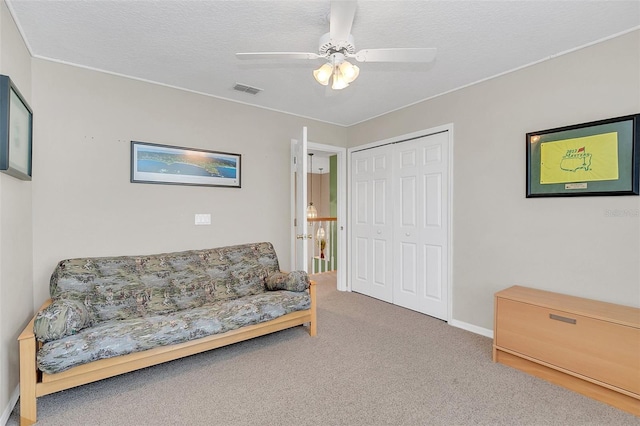 sitting room featuring ceiling fan, carpet floors, and a textured ceiling