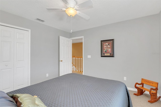 carpeted bedroom with ceiling fan, a textured ceiling, and a closet