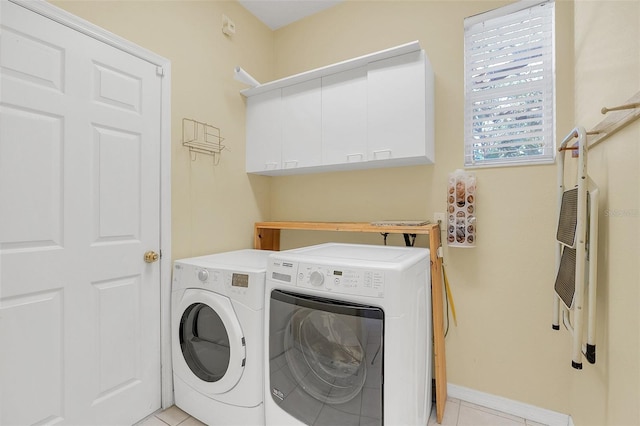 clothes washing area featuring light tile patterned flooring, cabinets, and washing machine and dryer