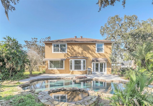 rear view of property featuring french doors, a swimming pool with hot tub, and a patio