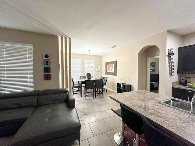 tiled living room with a notable chandelier and a textured ceiling