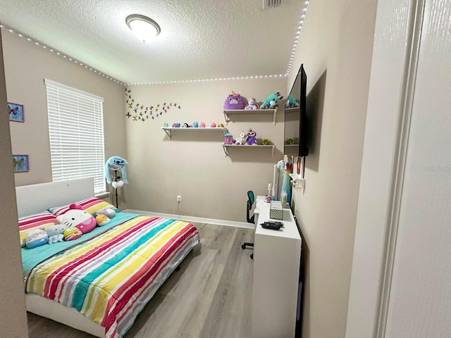 bedroom featuring light hardwood / wood-style flooring and a textured ceiling