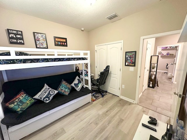 bedroom with a closet, a textured ceiling, and light wood-type flooring