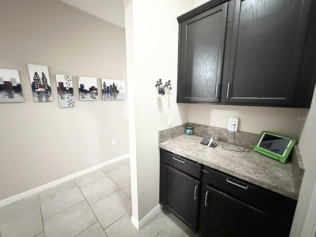 bar with light stone counters and light tile patterned flooring