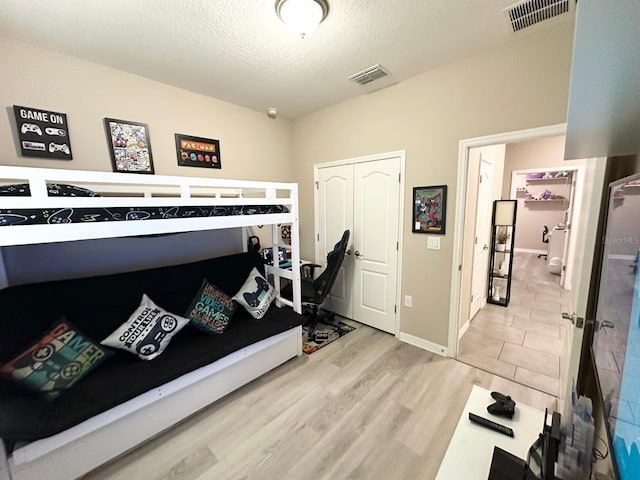 bedroom featuring light hardwood / wood-style floors, a closet, and a textured ceiling