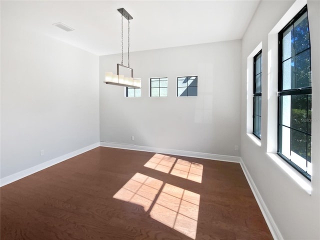 unfurnished room featuring dark hardwood / wood-style flooring, a healthy amount of sunlight, and an inviting chandelier