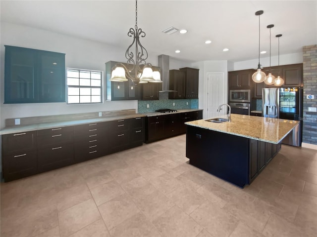 kitchen featuring appliances with stainless steel finishes, decorative light fixtures, an island with sink, sink, and dark brown cabinetry