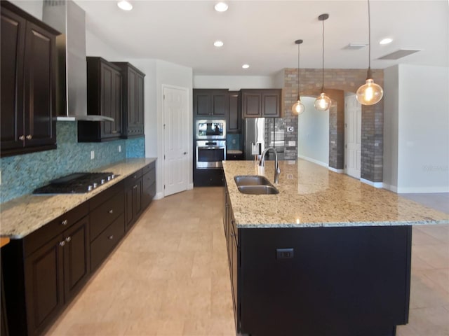 kitchen with a spacious island, sink, hanging light fixtures, and wall chimney range hood