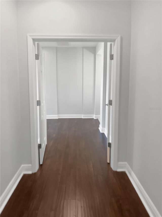 corridor with dark hardwood / wood-style flooring