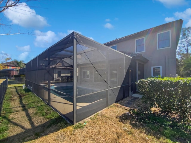 back of property with a pool and glass enclosure