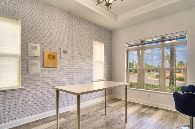 home office with crown molding, brick wall, hardwood / wood-style floors, and a tray ceiling