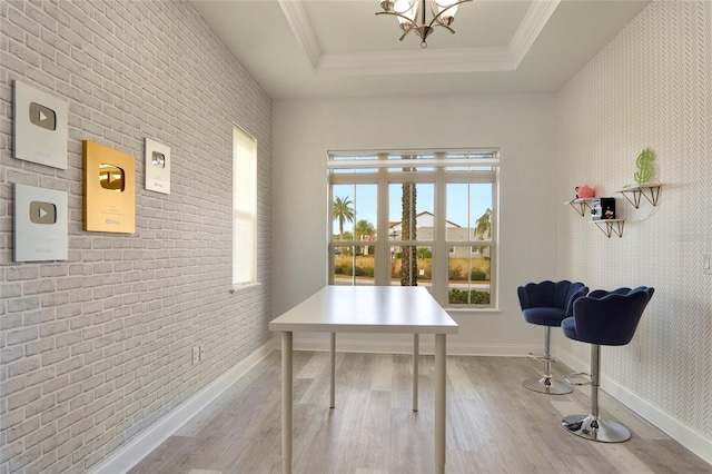 office with a tray ceiling, ornamental molding, brick wall, wood finished floors, and baseboards