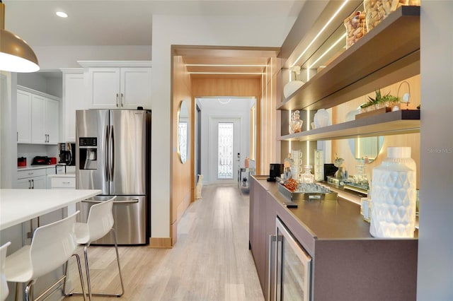 kitchen with stainless steel fridge, light hardwood / wood-style floors, beverage cooler, and white cabinets