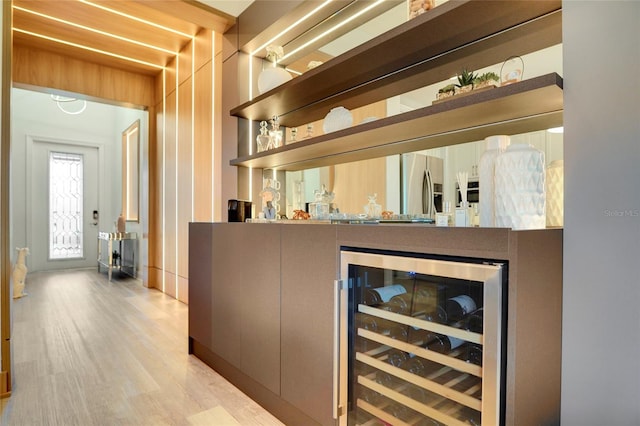 bar with wine cooler, stainless steel fridge, and light hardwood / wood-style flooring