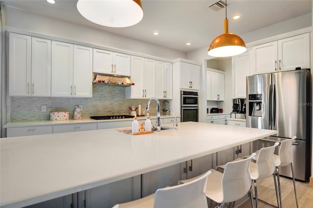 kitchen featuring white cabinetry, hanging light fixtures, ventilation hood, and appliances with stainless steel finishes