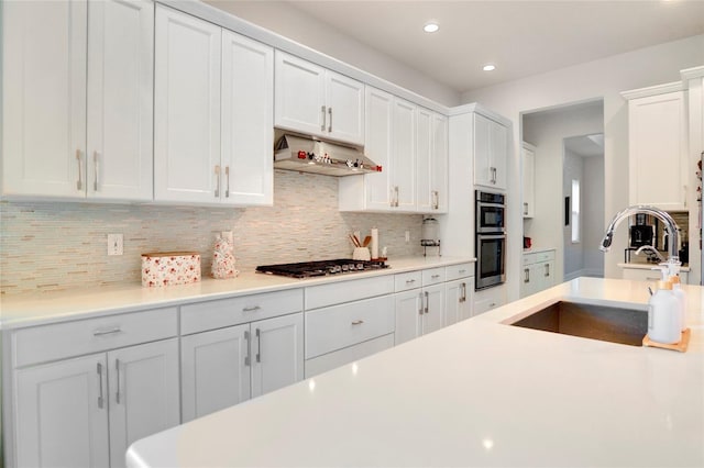 kitchen featuring backsplash, appliances with stainless steel finishes, white cabinetry, a sink, and under cabinet range hood