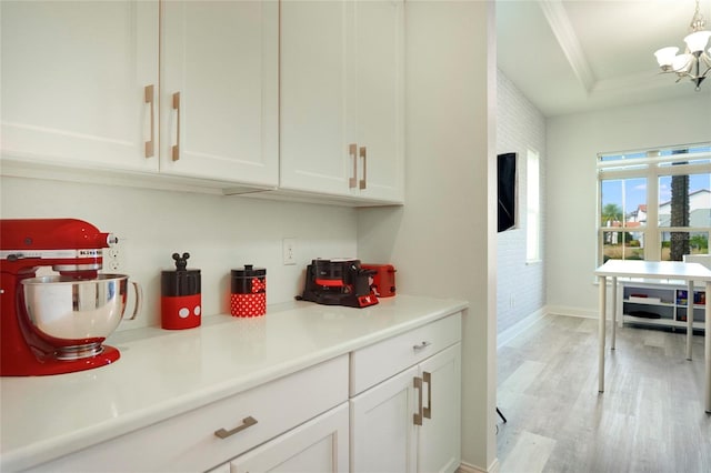 kitchen with light countertops, a tray ceiling, light wood-style flooring, and white cabinetry