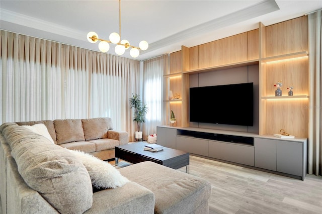 living room with a tray ceiling, a notable chandelier, crown molding, and light hardwood / wood-style floors