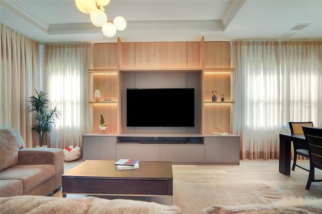 living room featuring crown molding, light hardwood / wood-style floors, and a raised ceiling