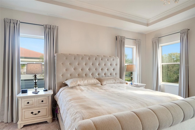 bedroom featuring ornamental molding, a tray ceiling, and light carpet