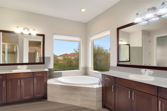 full bath with a garden tub, two vanities, a sink, and a shower stall