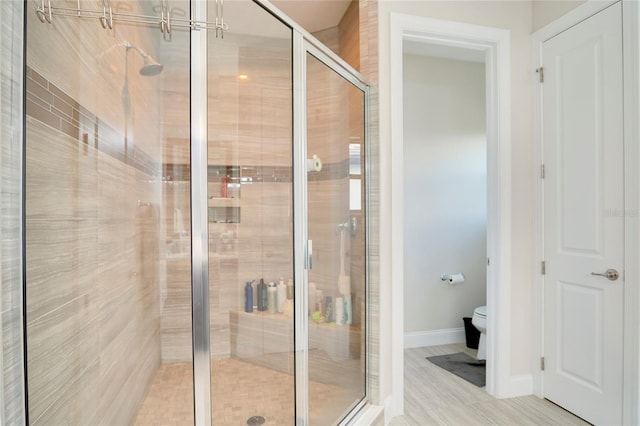 full bath featuring a stall shower, baseboards, and toilet