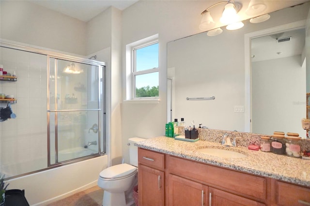 full bathroom featuring vanity, bath / shower combo with glass door, and toilet