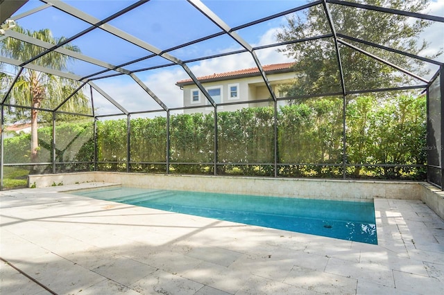 view of pool with glass enclosure and a patio area