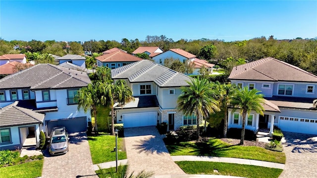 view of front of home featuring decorative driveway, a tile roof, stucco siding, an attached garage, and a residential view