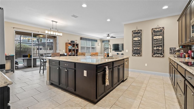 kitchen featuring pendant lighting, an island with sink, sink, light stone counters, and dark brown cabinets