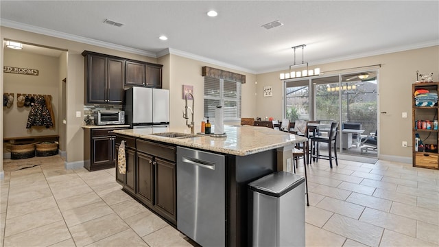 kitchen with stainless steel dishwasher, ornamental molding, hanging light fixtures, and a center island with sink