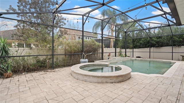 view of pool with an in ground hot tub, a patio area, and glass enclosure