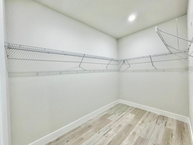 walk in closet with light hardwood / wood-style flooring