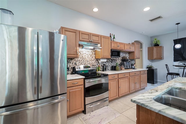 kitchen with light tile patterned flooring, light stone counters, decorative light fixtures, stainless steel appliances, and decorative backsplash