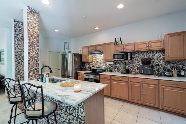 kitchen with light tile patterned flooring, sink, a breakfast bar area, stainless steel appliances, and decorative backsplash