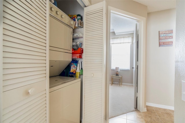 laundry room featuring light tile patterned flooring and stacked washer / drying machine