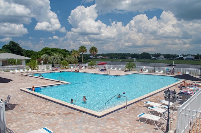 view of swimming pool featuring a water view and a patio area